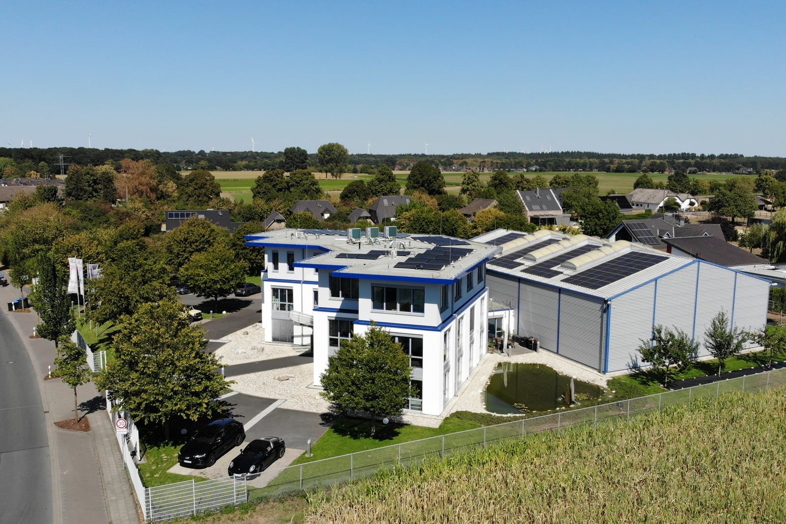 Weites Luftbild des Firmensitzes in Goch: Bürogebäude und Lagerhalle mit Blick über die umgebende Landschaft